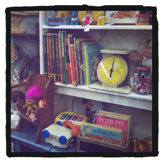 Vintage children’s books, toys, and antique shop treasures arranged on a shelf, evoking nostalgic Mother’s Day gift memories.